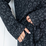 Woman wearing black button up pajamas in a monochromatic leopard print close up on pant pocket detail