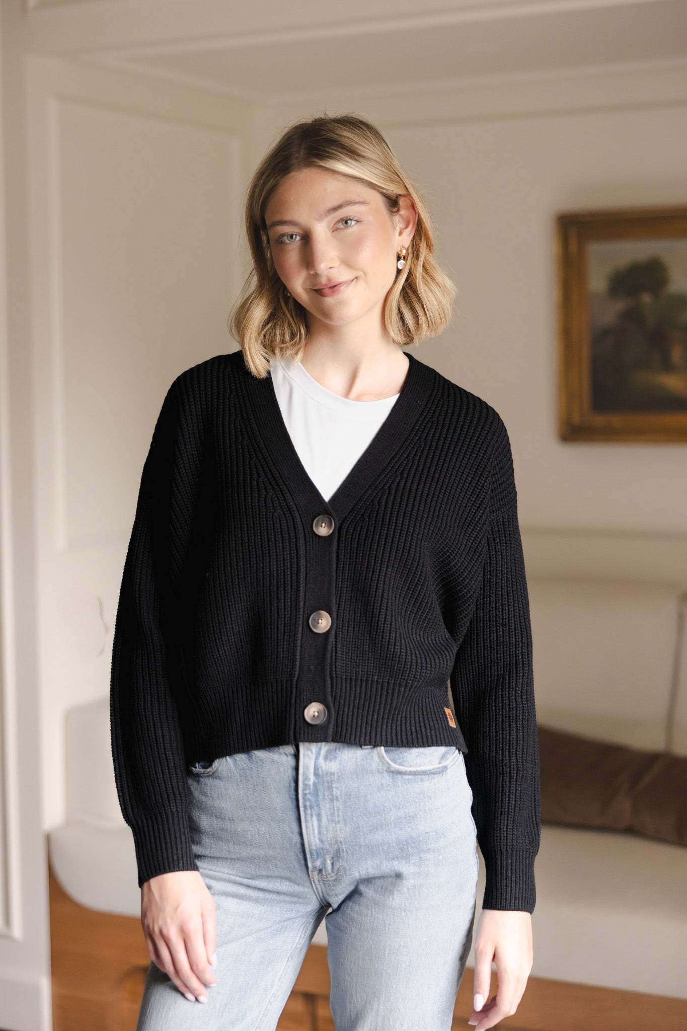 Woman soft smiling wearing a cropped cardigan in midnight with jeans.
