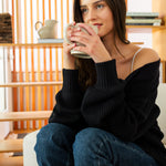 Woman sitting on a couch holding a mug in a cozy living room.