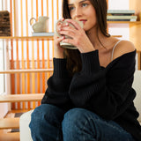Woman sitting on a couch holding a mug in a cozy living room.