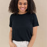 Female model wearing the Women's Crew Neck Tee in Midnight paired with white pants