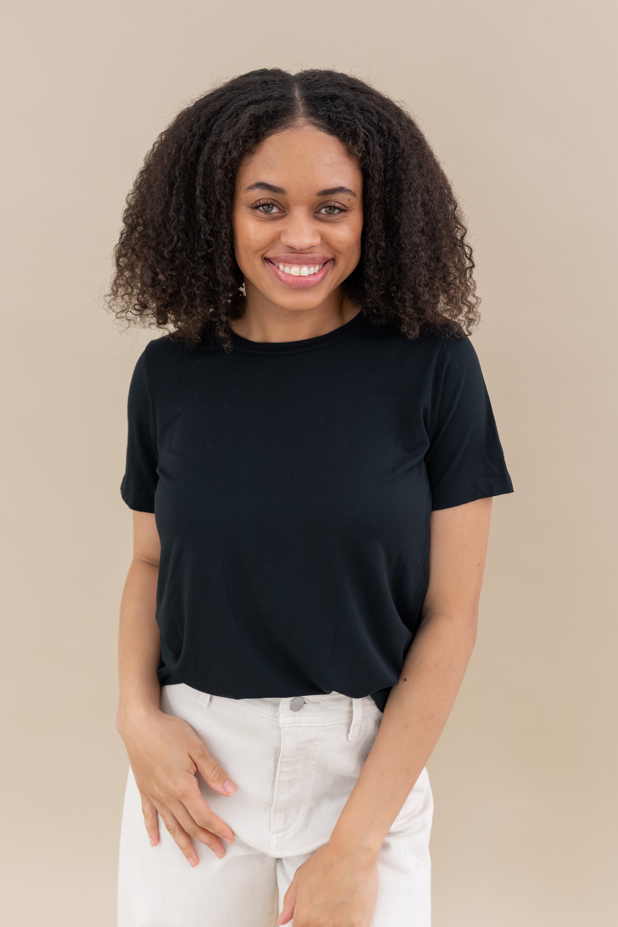 Female model wearing the Women's Crew Neck Tee in Midnight paired with white pants