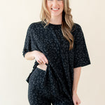 Woman modeling Women’s Biker Short Set in Midnight Leopard slightly lifting shirt to show elastic waist of shorts