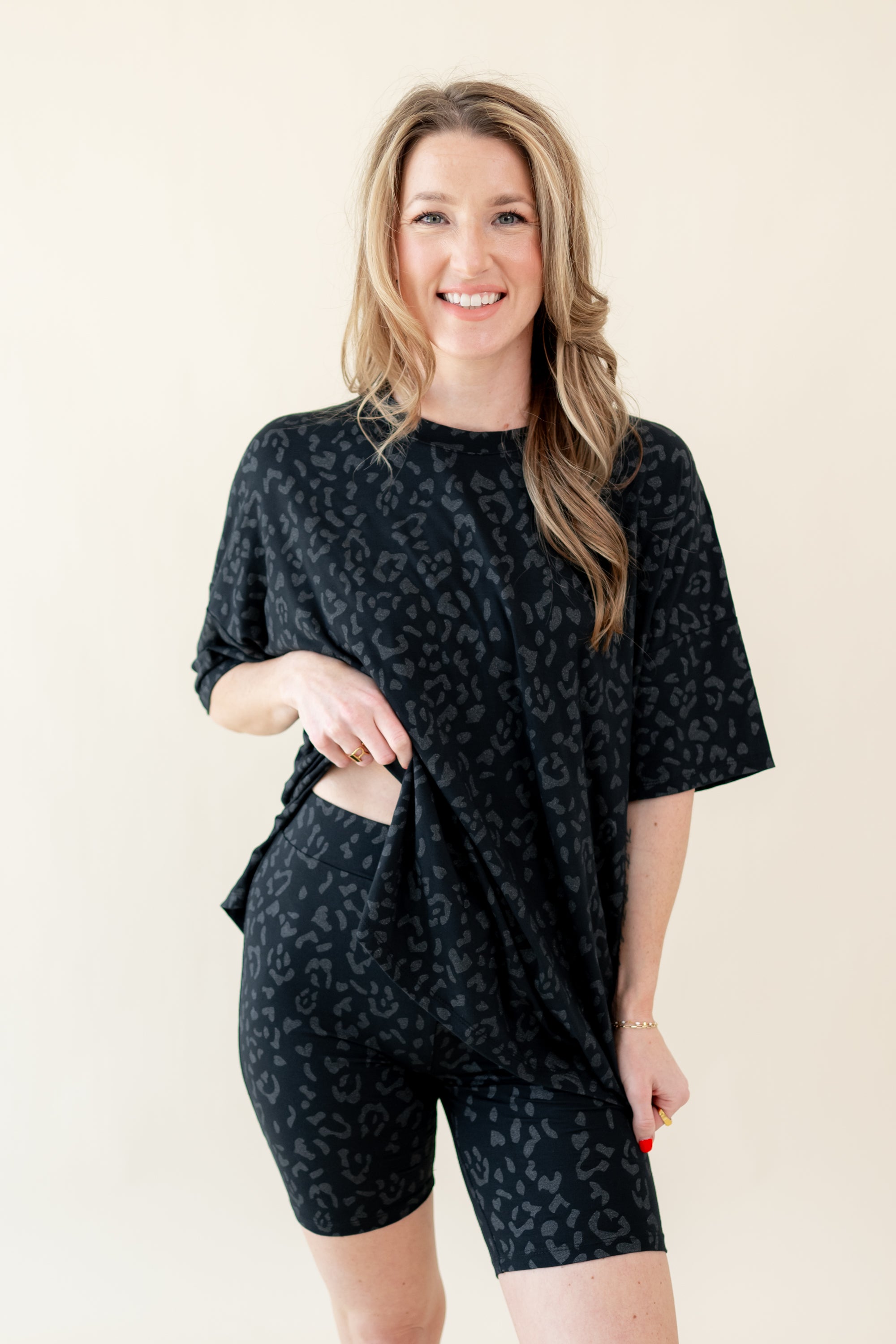 Woman modeling Women’s Biker Short Set in Midnight Leopard slightly lifting shirt to show elastic waist of shorts