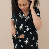 Woman modeling Women’s Short Sleeve Pajama Set in Big Midnight Magnolia with the bottom buttons unbuttoned to show waistband of shorts.