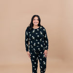 Woman wearing a Big Midnight Magnolia floral pajama set on a beige background