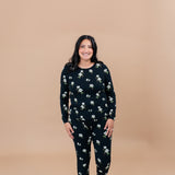 Woman wearing a Big Midnight Magnolia floral pajama set on a beige background