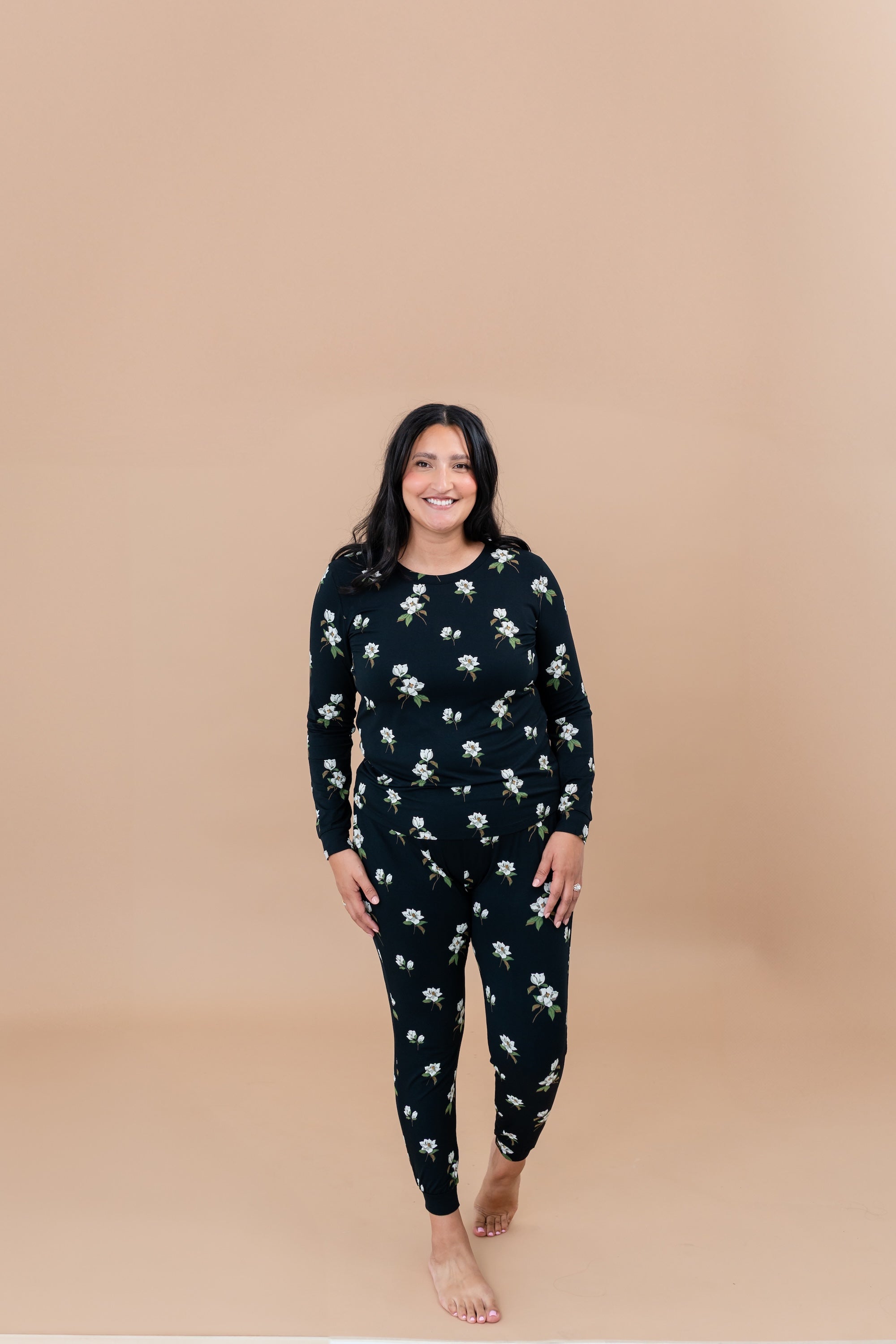 Woman wearing a Big Midnight Magnolia floral pajama set on a beige background