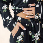 Black floral dress with white flowers and green leaves, worn by a person.