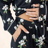 Black floral dress with white flowers and green leaves, worn by a person.