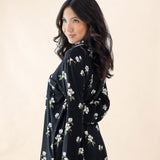 Woman wearing a black floral dress against a beige background