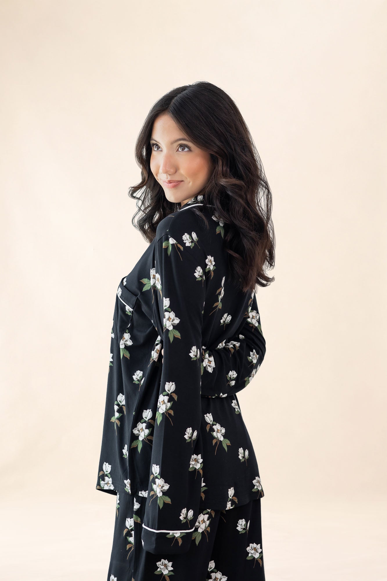 Woman wearing a black floral dress against a beige background