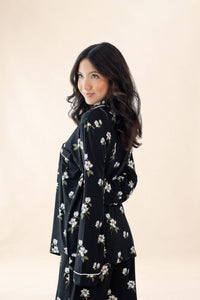 Woman wearing a black floral dress against a beige background