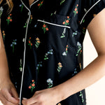 Model showing the front buttons of Women's Short Sleeve Cropped Pajama Set in Midnight Wildflower print on a beige background ---PJ 2