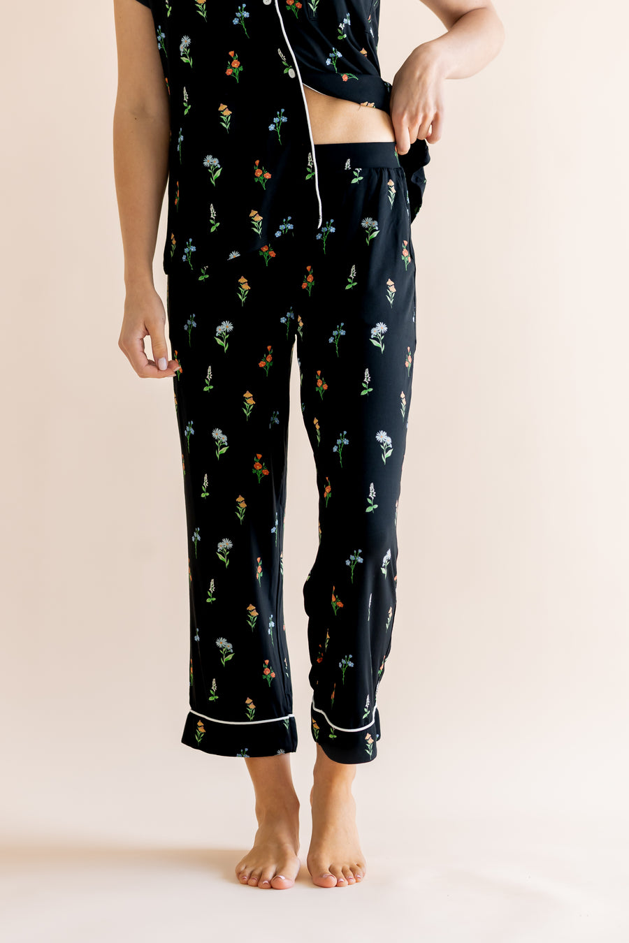 Model show casing the cropped pajama of Women's Short Sleeve Cropped Pajama Set in Midnight Wildflower print on a beige background