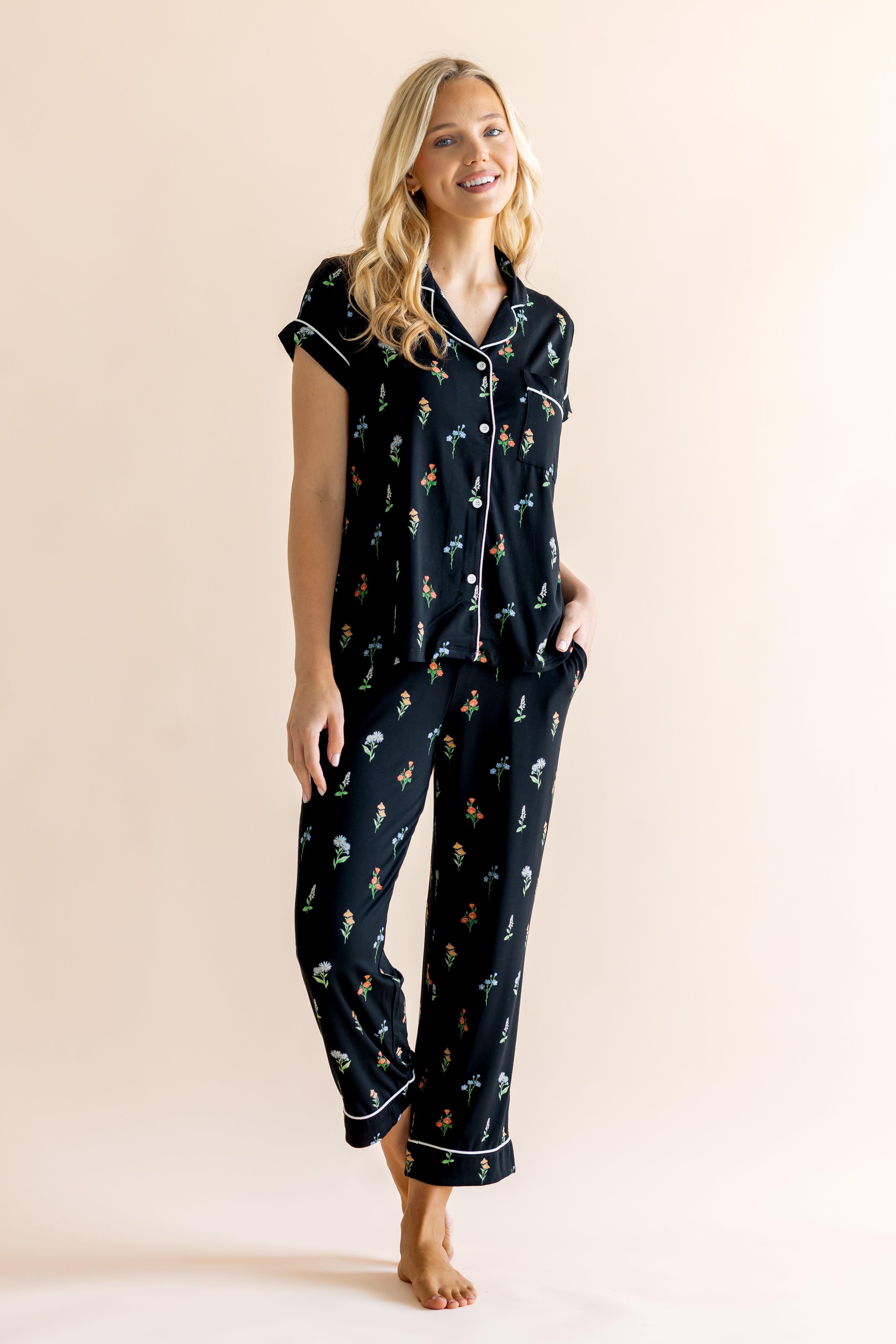 Model posing in Women's Short Sleeve Cropped Pajama Set in Midnight Wildflower print on a beige background 
