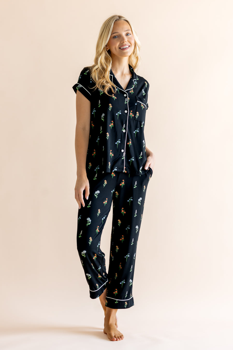 Model posing in Women's Short Sleeve Cropped Pajama Set in Midnight Wildflower print on a beige background