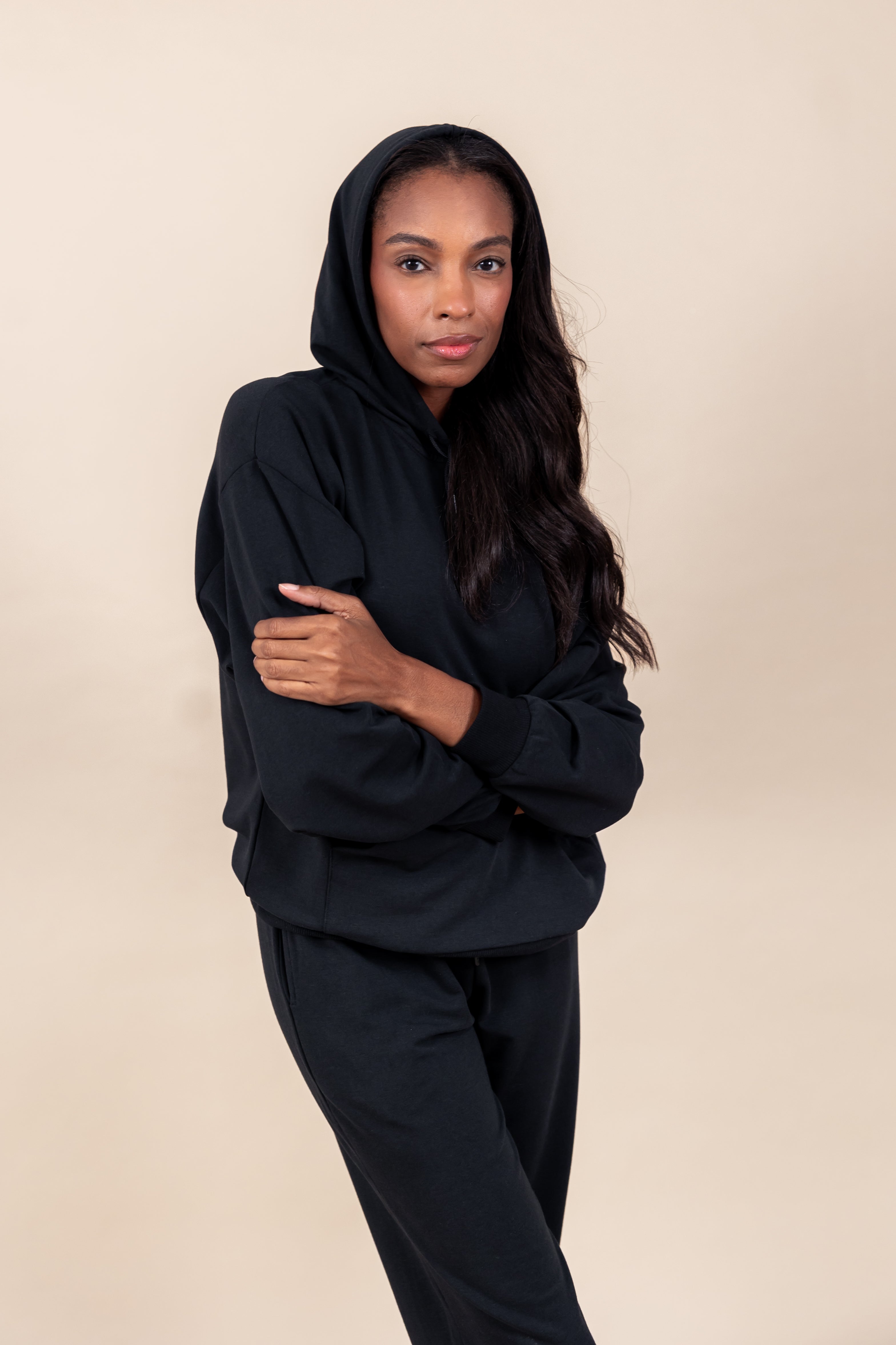 Woman wearing Women's Hoodie in Midnight color with crossed hands over similar color women's jogger pants on a beige background
::: Model is 5'9" wearing size M ///