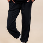 Woman wearing Women's Jogger Pants in Midnight color with pockets under a similar color Hoodie on a beige background