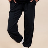 Woman wearing Women's Jogger Pants in Midnight color with pockets under a similar color Hoodie on a beige background