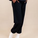 Side view of Woman wearing Women's Jogger Pants in Midnight color with pockets under a similar color Hoodie on a beige background