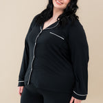 Female model wearing Kyte Baby's Women's Long Sleeve Pajama Set in Midnight with Cloud Trim
