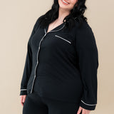 Female model wearing Kyte Baby's Women's Long Sleeve Pajama Set in Midnight with Cloud Trim
