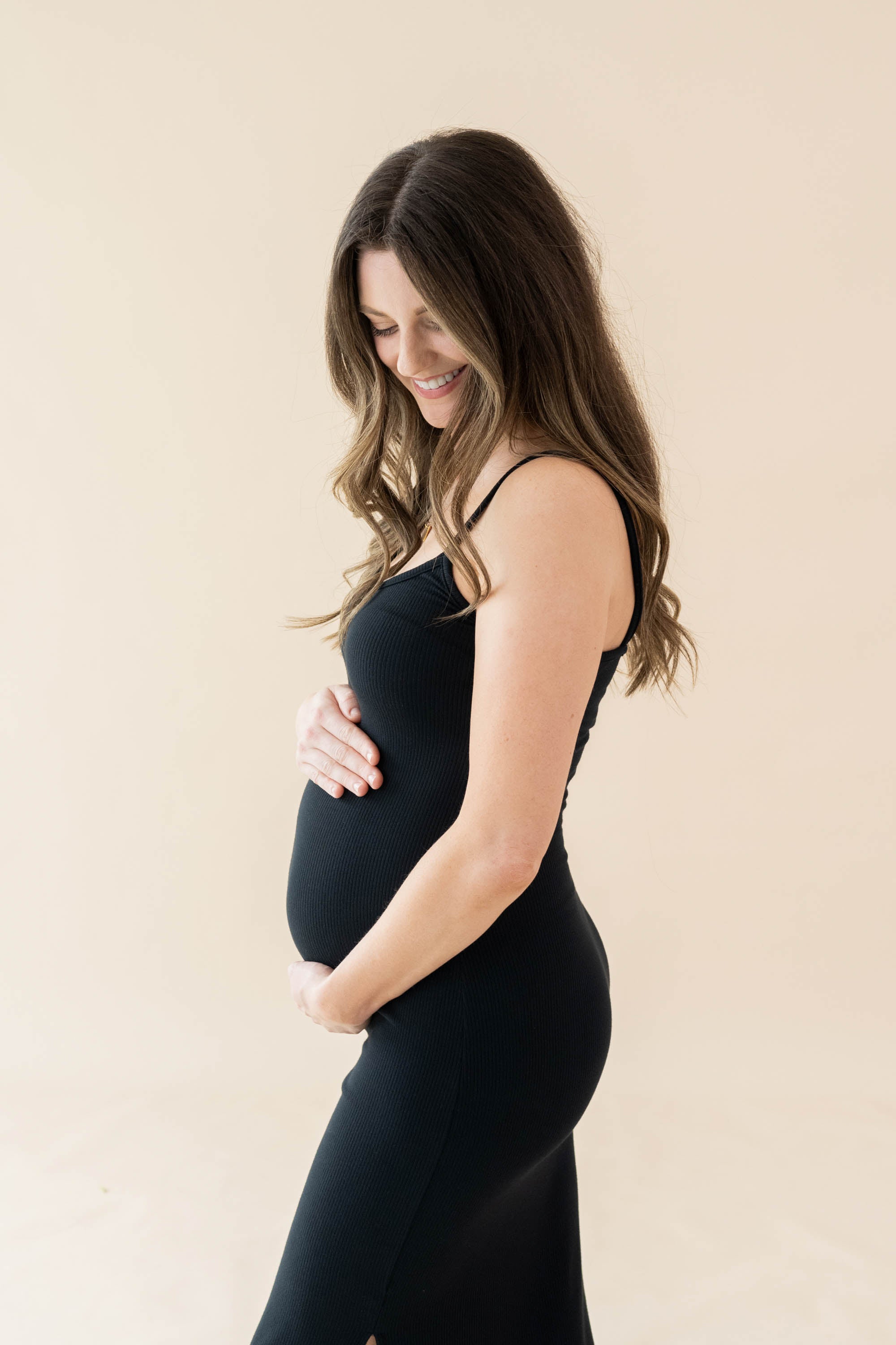 Expectant mother cradling her baby bump wearing the Women's Ribbed Cami Dress in Midnight
