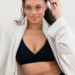 Woman in black bralette and underwear with a cream robe 