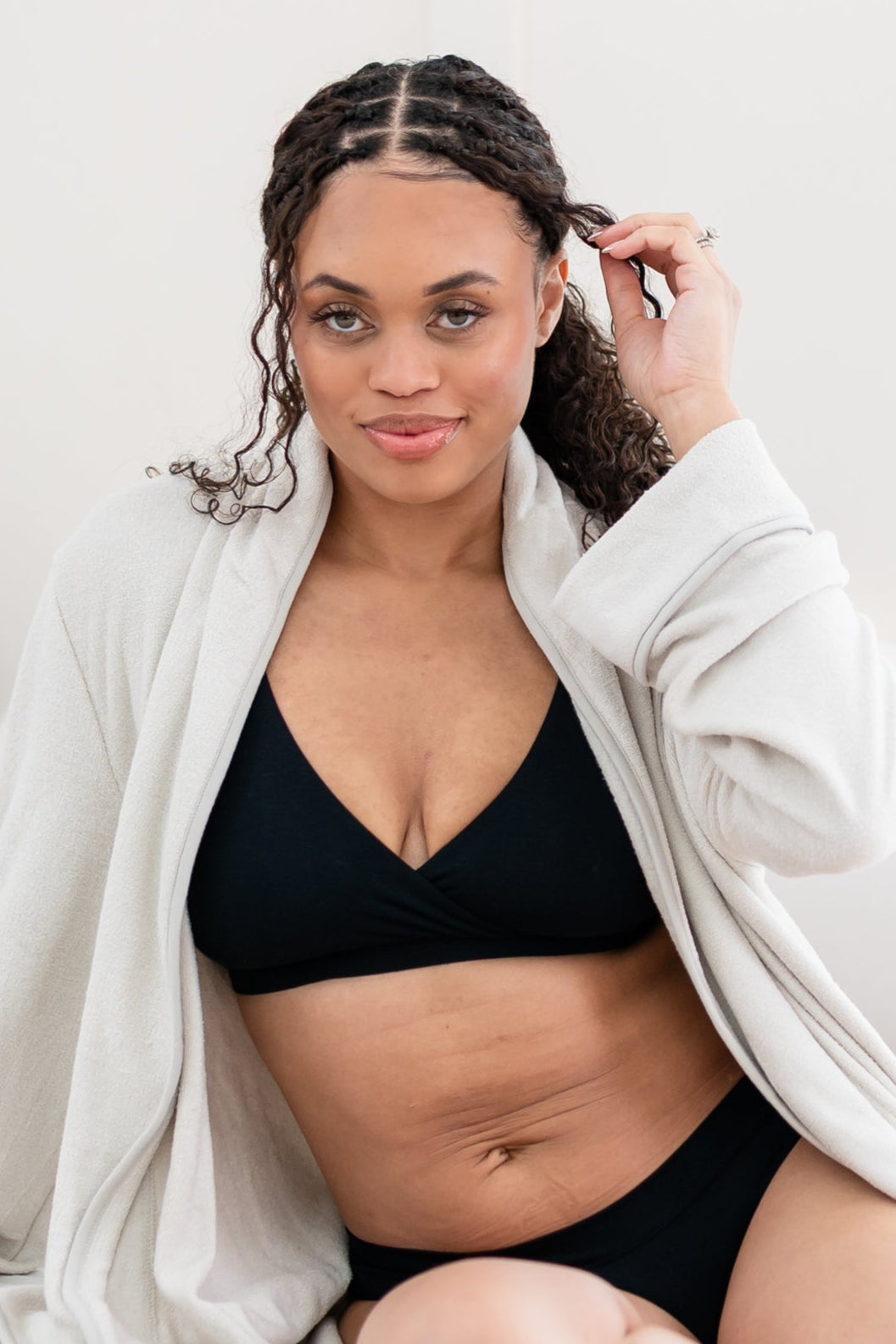 Woman in black bralette and underwear with a cream robe 
