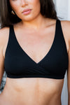 Black bra worn by a person against a neutral background