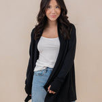 Female model standing wearing the Women's French Terry Wrap Top in Midnight paired with a white shirt and light wash jeans