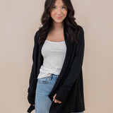Female model standing wearing the Women's French Terry Wrap Top in Midnight paired with a white shirt and light wash jeans