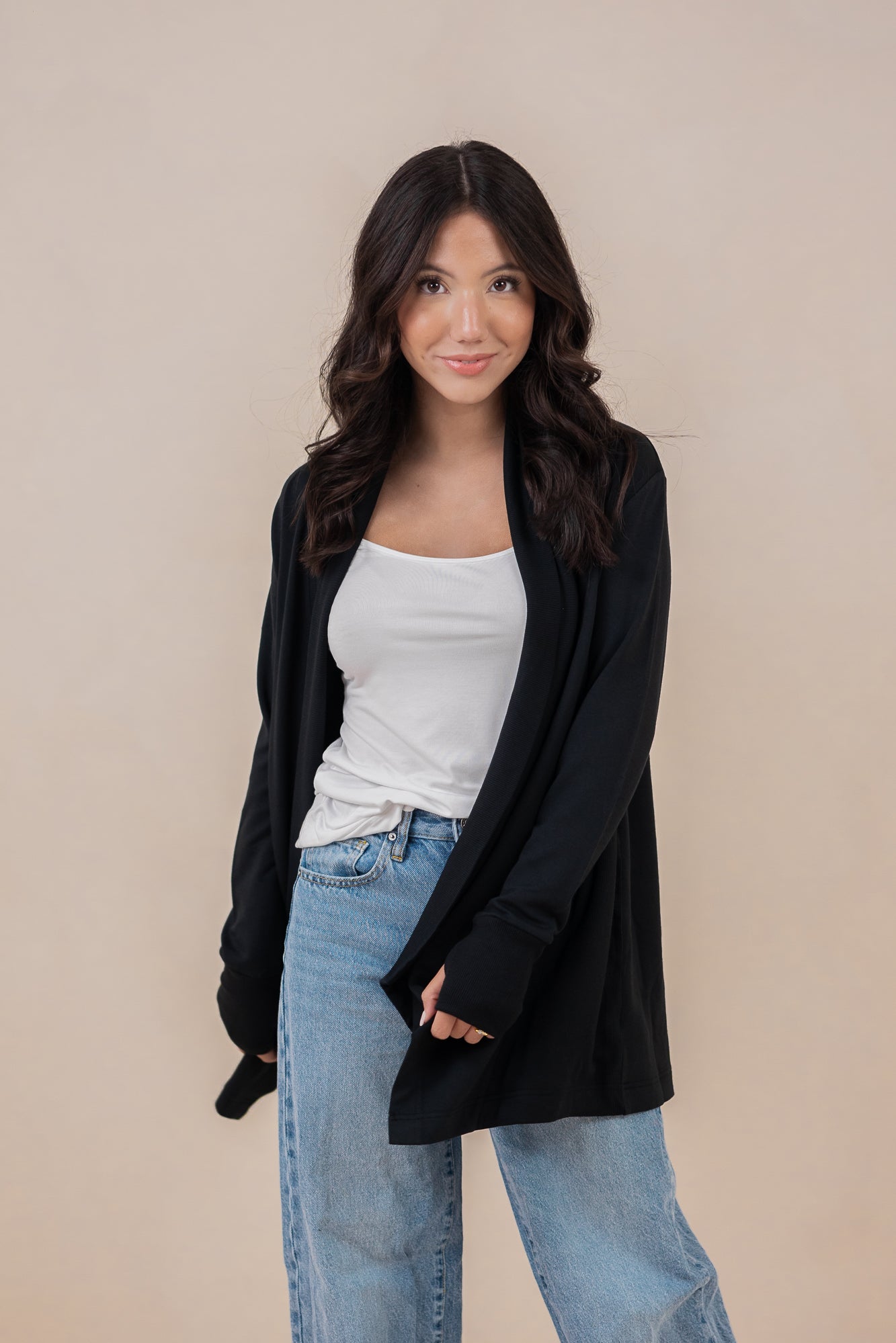 Female model standing wearing the Women's French Terry Wrap Top in Midnight paired with a white shirt and light wash jeans