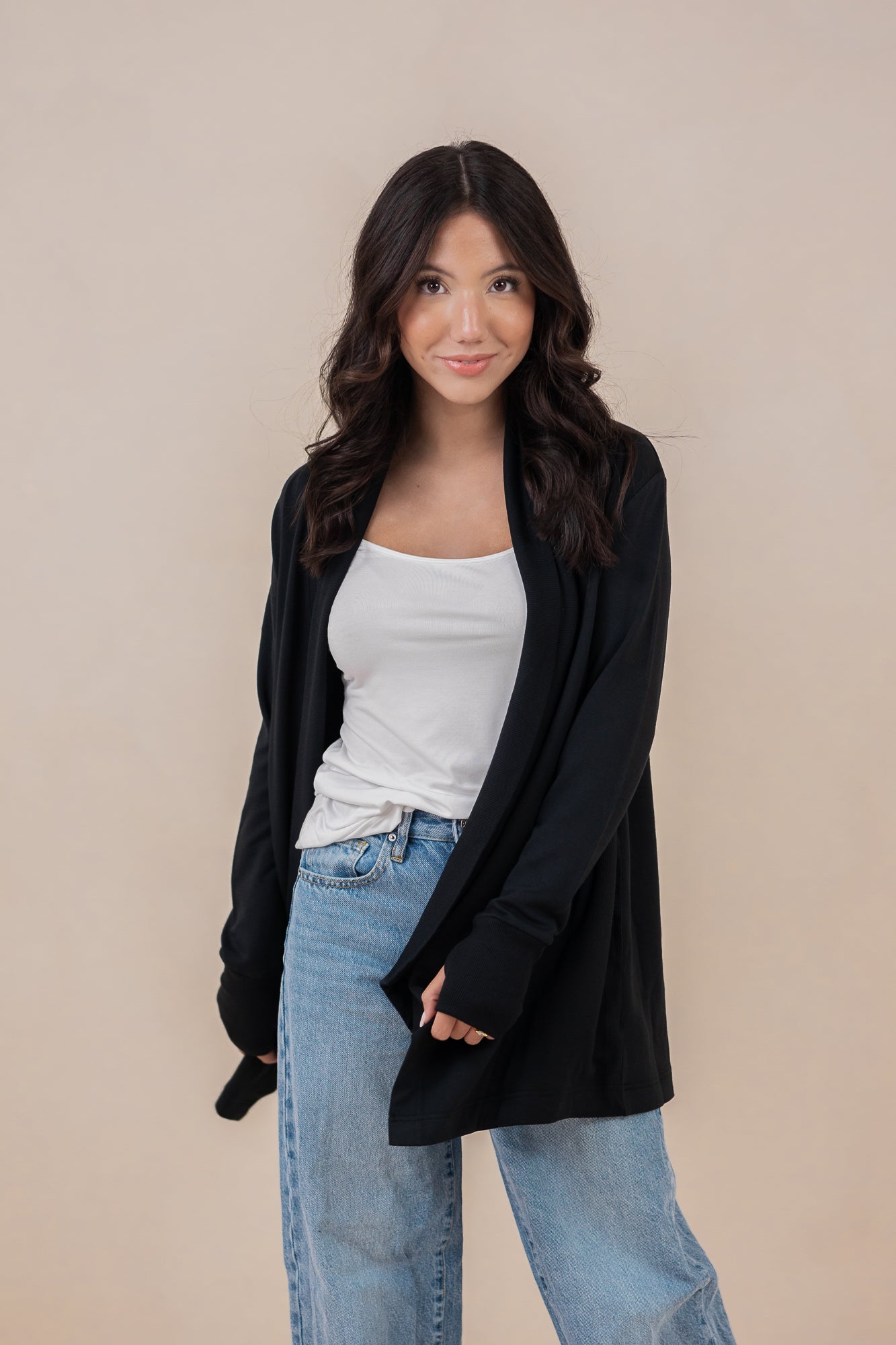 Female model standing wearing the Women's French Terry Wrap Top in Midnight paired with a white shirt and light wash jeans