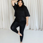 Female standing on one leg wearing the Bamboo Flex Women’s Leggings in Midnight and short sleeve tee
