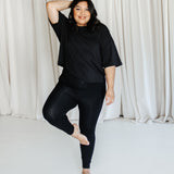 Female standing on one leg wearing the Bamboo Flex Women’s Leggings in Midnight and short sleeve tee