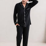 Man standing with one hand on his head while modeling the Kyte Men's Long Sleeve Pajama Set in Midnight