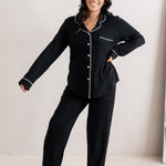 Model smiling with one hand on hip and one hand extended while wearing the Women's Long Sleeve Pajama Set in Midnight with Cloud Trim