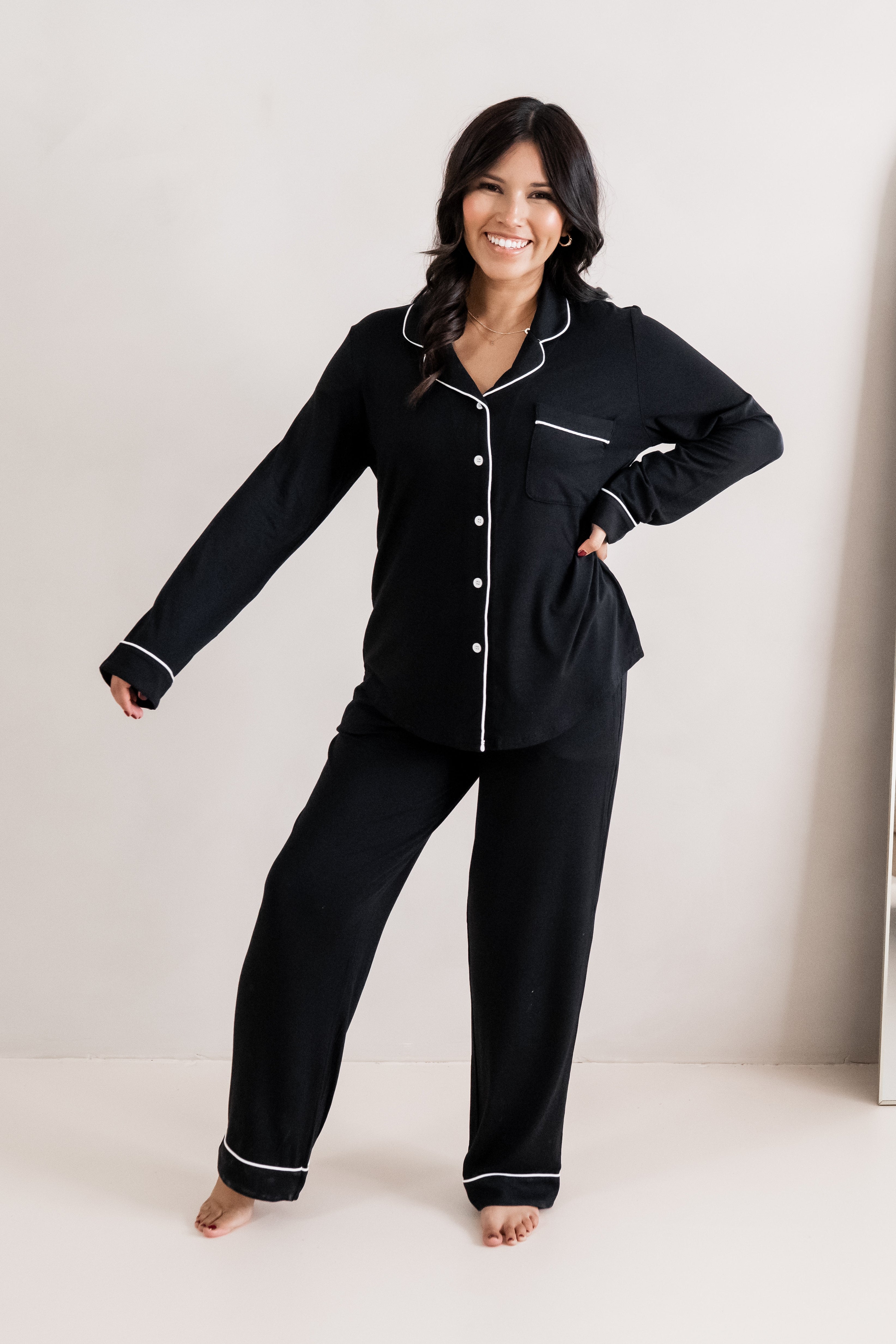 Model smiling with one hand on hip and one hand extended while wearing the Women's Long Sleeve Pajama Set in Midnight with Cloud Trim