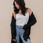 Model looking downwards with the Women's French Terry Wrap Top in Midnight off her shoulders paired with light wash jeans