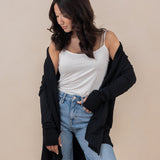 Model looking downwards with the Women's French Terry Wrap Top in Midnight off her shoulders paired with light wash jeans