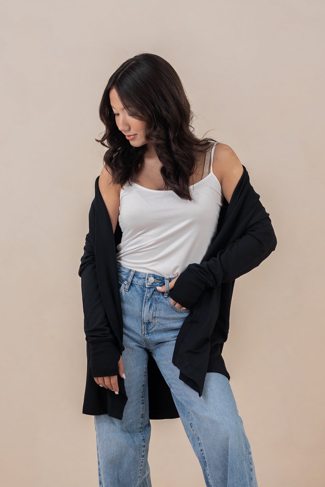 Model looking downwards with the Women's French Terry Wrap Top in Midnight off her shoulders paired with light wash jeans