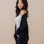Woman standing sideways with one hand in her pocket, wearing the Kyte Women's French Terry Wrap Top in Midnight paired with jeans 