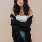 Woman wearing the Kyte Women's French Terry Wrap Top in Midnight off of her shoulders paired with a cami in cloud 