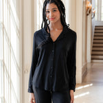 Woman soft smiling against a window wearing a long sleeve pajama set in midnight
::: Model is 5'11" wearing size S ///
---PJ 2