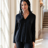 Woman soft smiling against a window wearing a long sleeve pajama set in midnight
::: Model is 5'11" wearing size S ///
---PJ 2