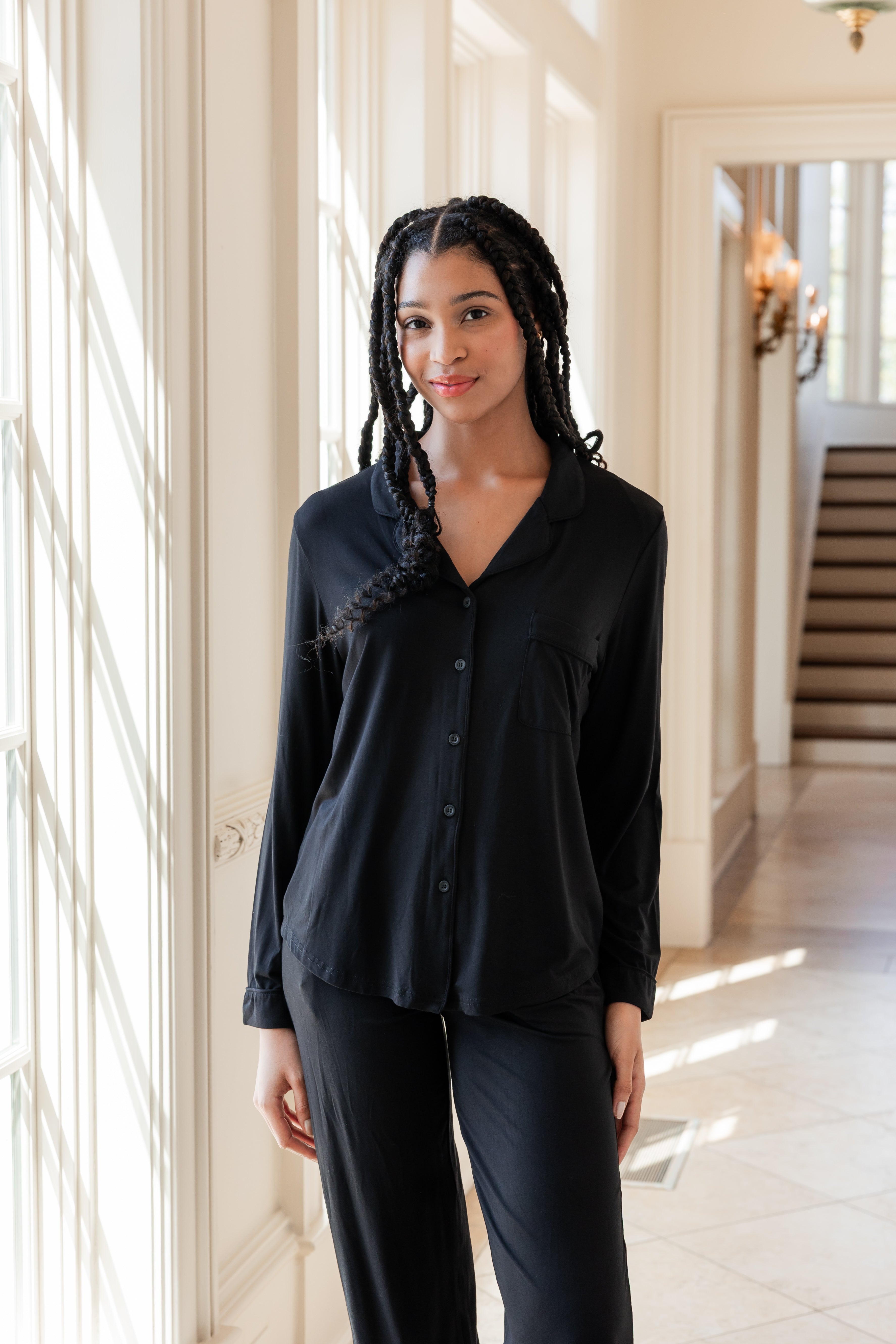 Woman soft smiling against a window wearing a long sleeve pajama set in midnight
::: Model is 5'11" wearing size S ///
---PJ 2
