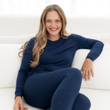 Model sitting in bed wearing the Women's Jogger Pajama Set in Navy