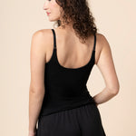 Model showcasing the back side and straps on the Women's Nursing Tank in Midnight in front of a beige back ground 